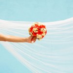 Eine Braut mit langem weißen Schleiher und Brautstrauß